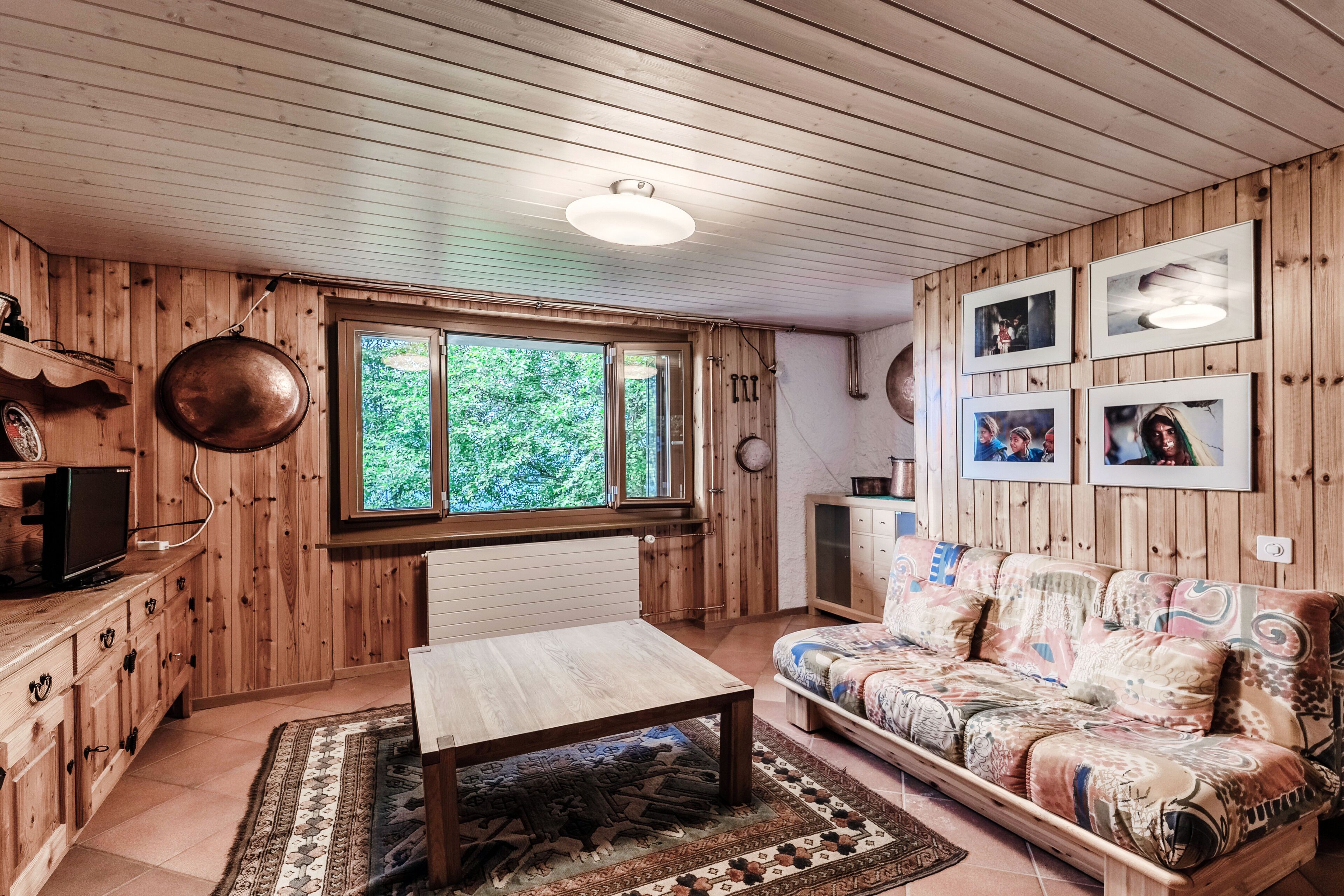 Een houten interieur met een bank, een tafel en een televisie.