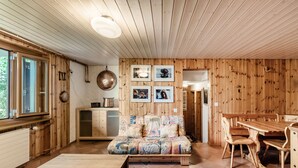 Un interior de madera con sofá, mesa de comedor y sillas.