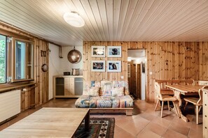 A wooden interior with a sofa, dining table, and chairs.
