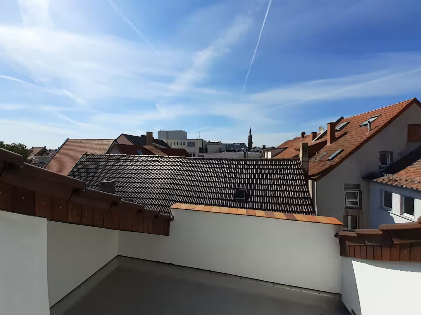 Une terrasse sur le toit offrant une vue sur les bâtiments environnants et un ciel dégagé.