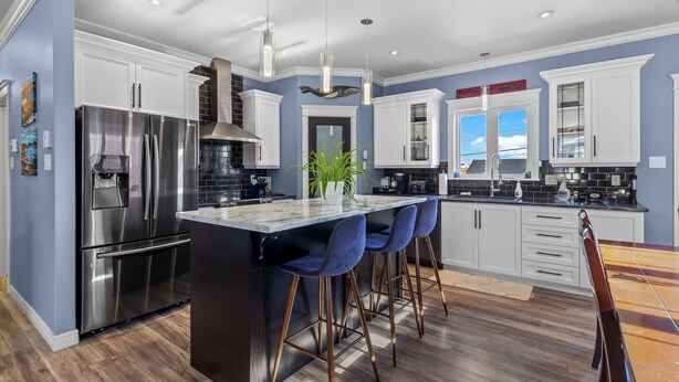 A modern kitchen with a central island, bar stools, stainless steel appliances, and a view to the outside. - Family-Friendly 3BR, HotTub, Patio, Bar, Fireplace (Paradise)