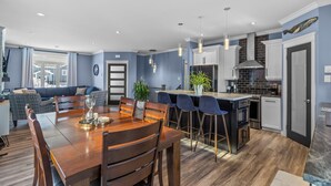 A modern kitchen with a central island, bar stools, and a dining table with chairs. - Family-Friendly 3BR, HotTub, Patio, Bar, Fireplace (Paradise)