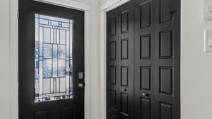 A black door with a glass panel and a modern light fixture above it. - Family-Friendly 3BR, HotTub, Patio, Bar, Fireplace (Paradise)