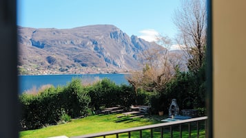 A view of a mountainous landscape with a lake, a grassy area with picnic tables, and a stone structure.