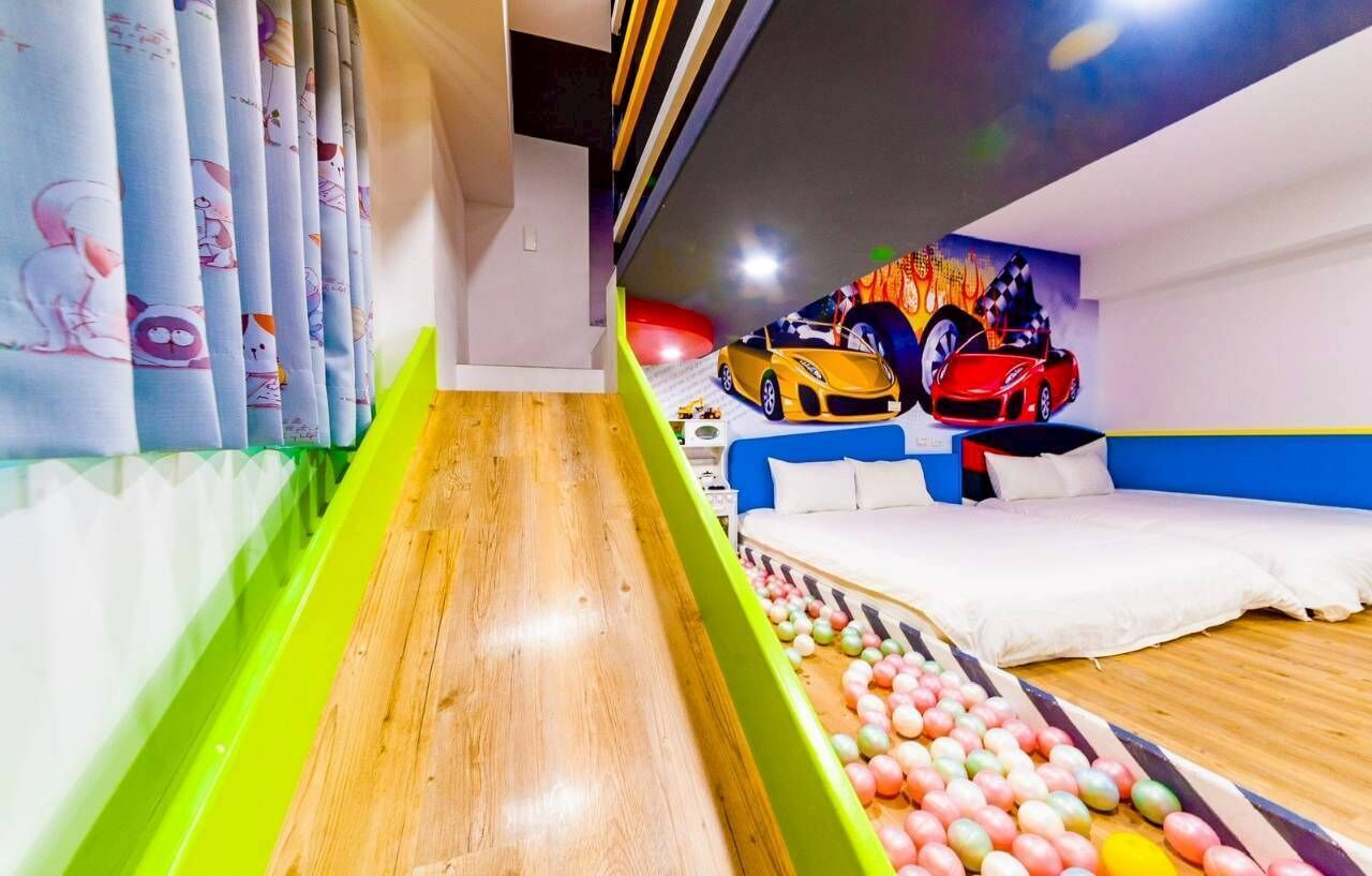 A children's play area with a slide, colorful balls, and a bed with pillows.