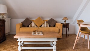 Un salon confortable avec un canapé, une table basse sur laquelle est posé un jeu d’échecs, une lampe et un fauteuil.