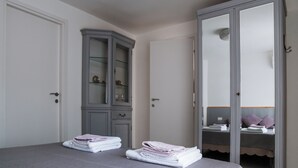 Une chambre à coucher avec un lit, une armoire grise et une armoire avec des portes miroir.