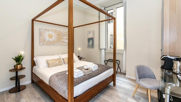 Un lit à baldaquin avec un cadre en bois, une petite table de chevet avec une plante, une chaise et un bureau avec une autre chaise.