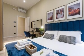 Ein Hotelzimmer mit einem großen Bett, einem Schreibtisch und einem Stuhl. An der Wand hängen drei gerahmte Bilder.