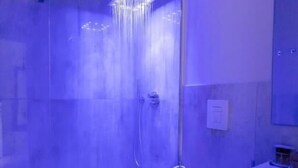 Une salle de bain moderne avec une douche à parois de verre, des toilettes blanches et un meuble-lavabo avec un miroir.