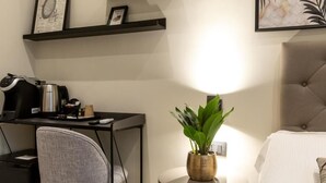 Une chambre moderne équipée d’un bureau, d’une chaise et d’une table de chevet agrémentée d’une plante.