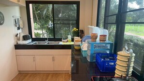A kitchen with a black countertop, wooden cabinets, a window with a view of greenery, and various kitchen items.