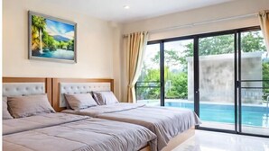 A bedroom with a large bed, a painting of a tropical scene, and a view of a swimming pool through a glass door.