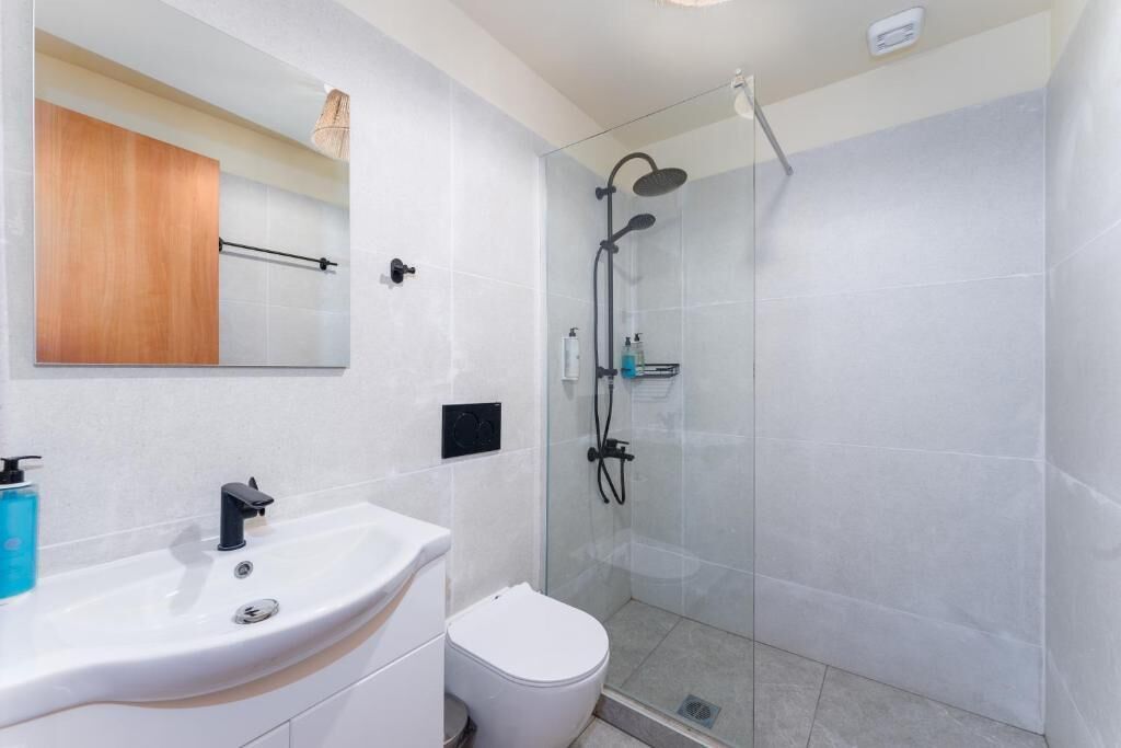 A bathroom with a white sink, a toilet, and a glass-enclosed shower area.