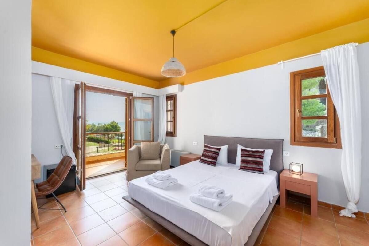 A bedroom with a large bed, a chair, a nightstand, and a window with curtains.