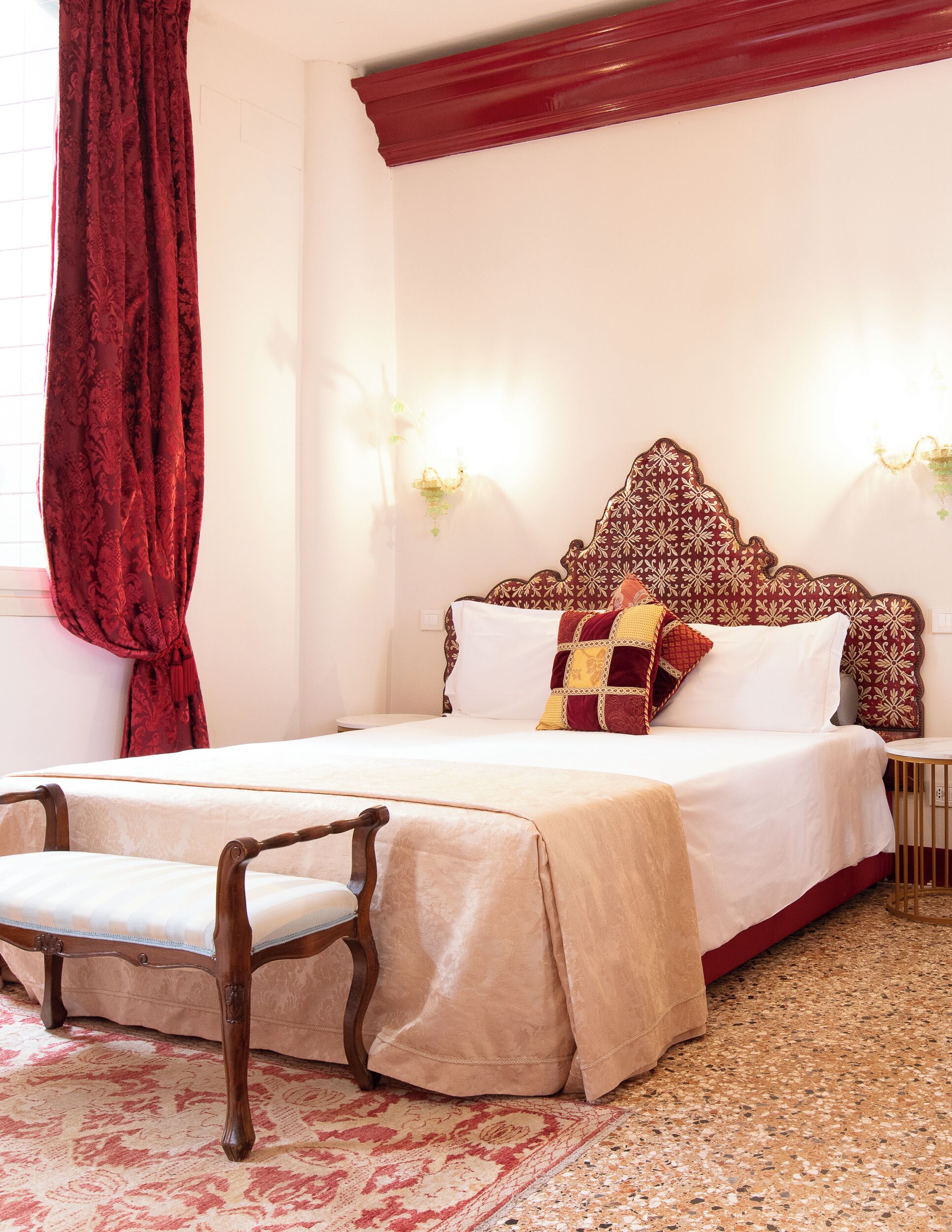 A neatly arranged bedroom with a bed, a chair, a nightstand, and a wall-mounted lamp.
