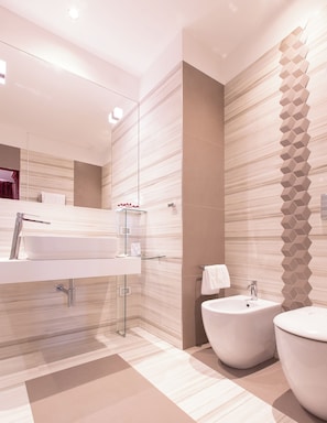 Une salle de bain moderne avec un grand miroir, un lavabo blanc, un bidet et des toilettes.