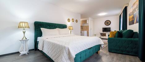 A modern bedroom with a large bed, a green sofa, and a small desk area.