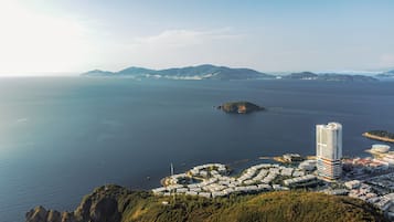 A coastal cityscape with a prominent high-rise hotel, a marina, and a residential area with a hilly backdrop.