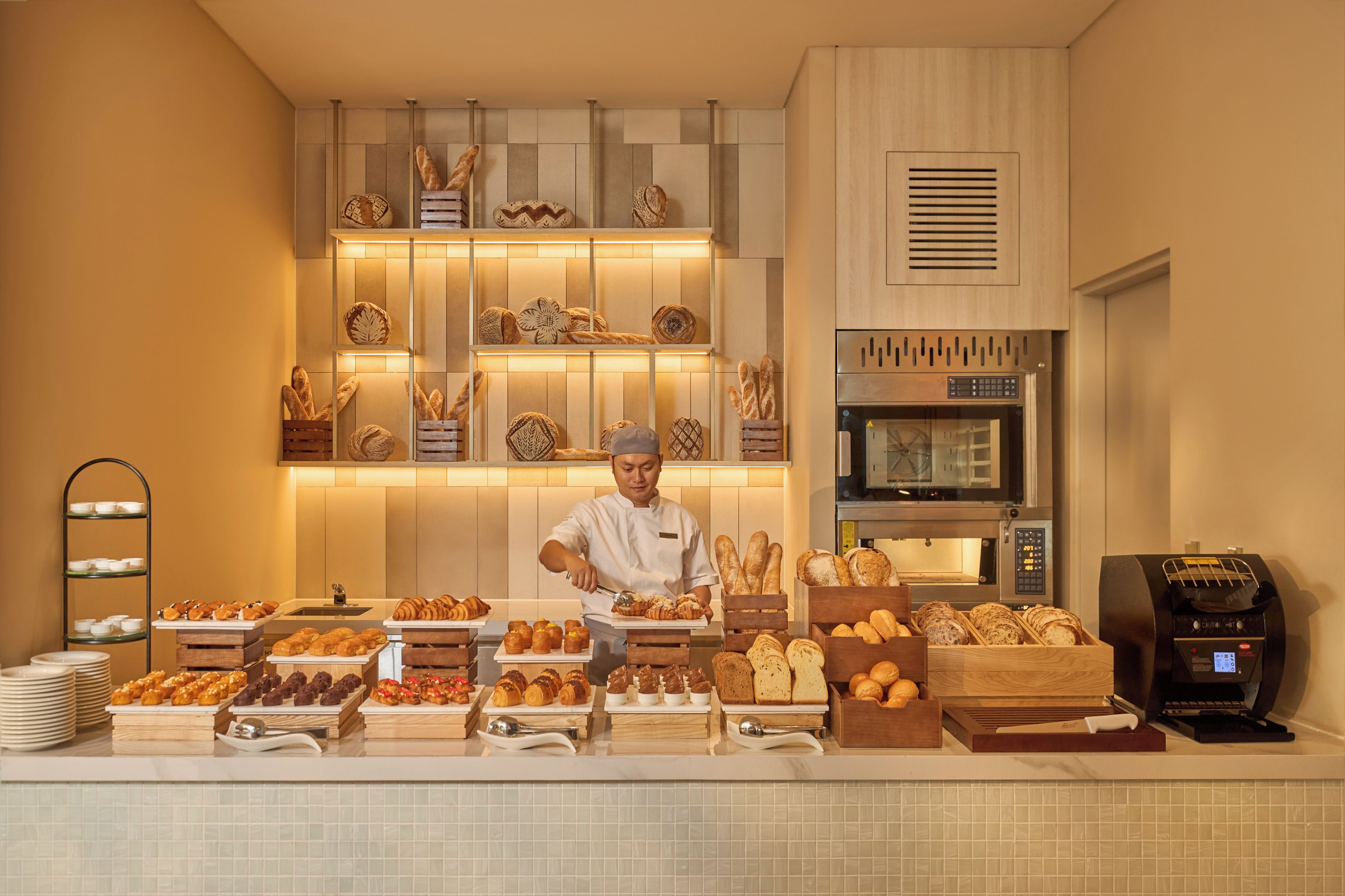 A bakery counter with various baked goods, a chef, and a commercial oven.