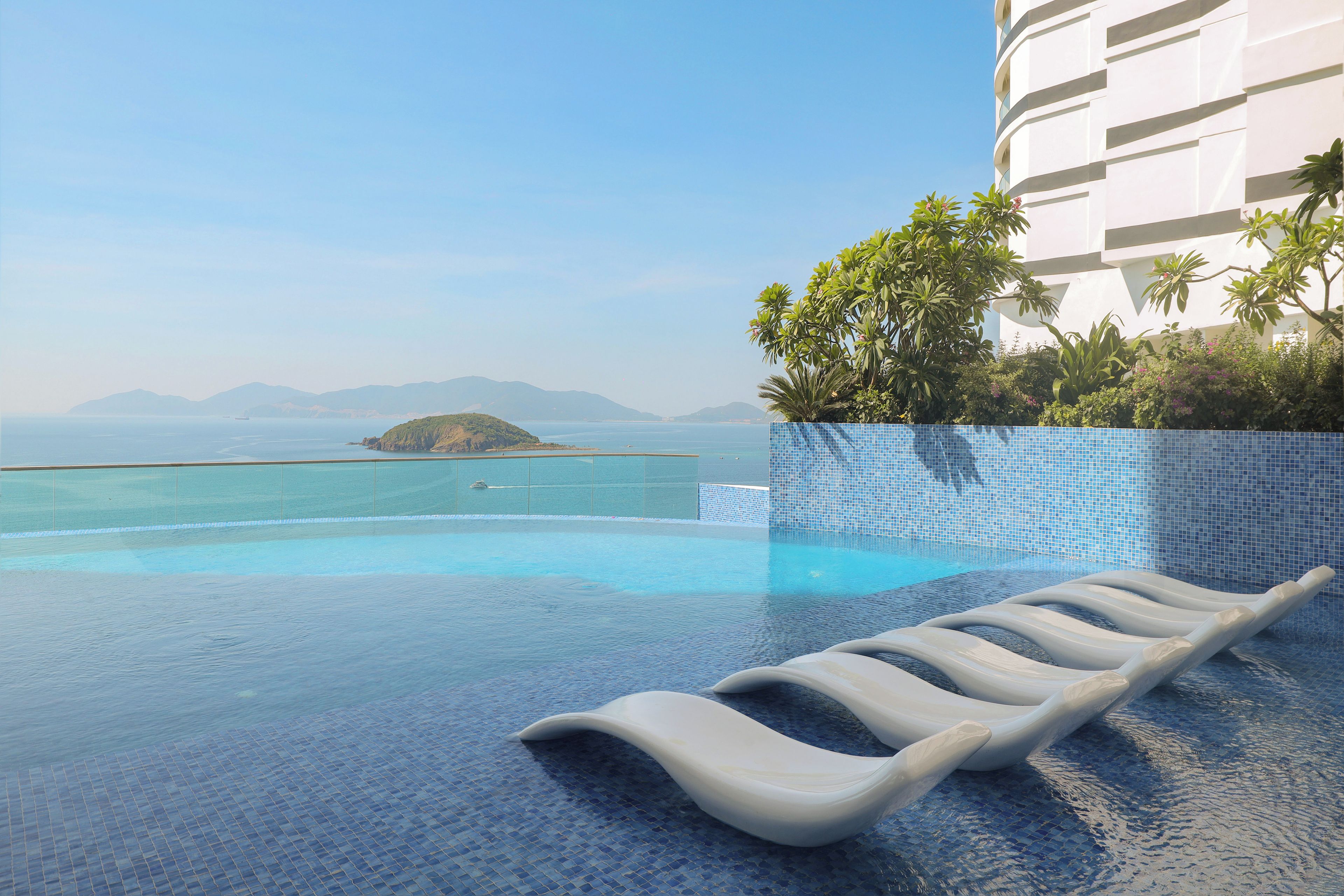 A pool with a clear view of the sea and mountains in the background.