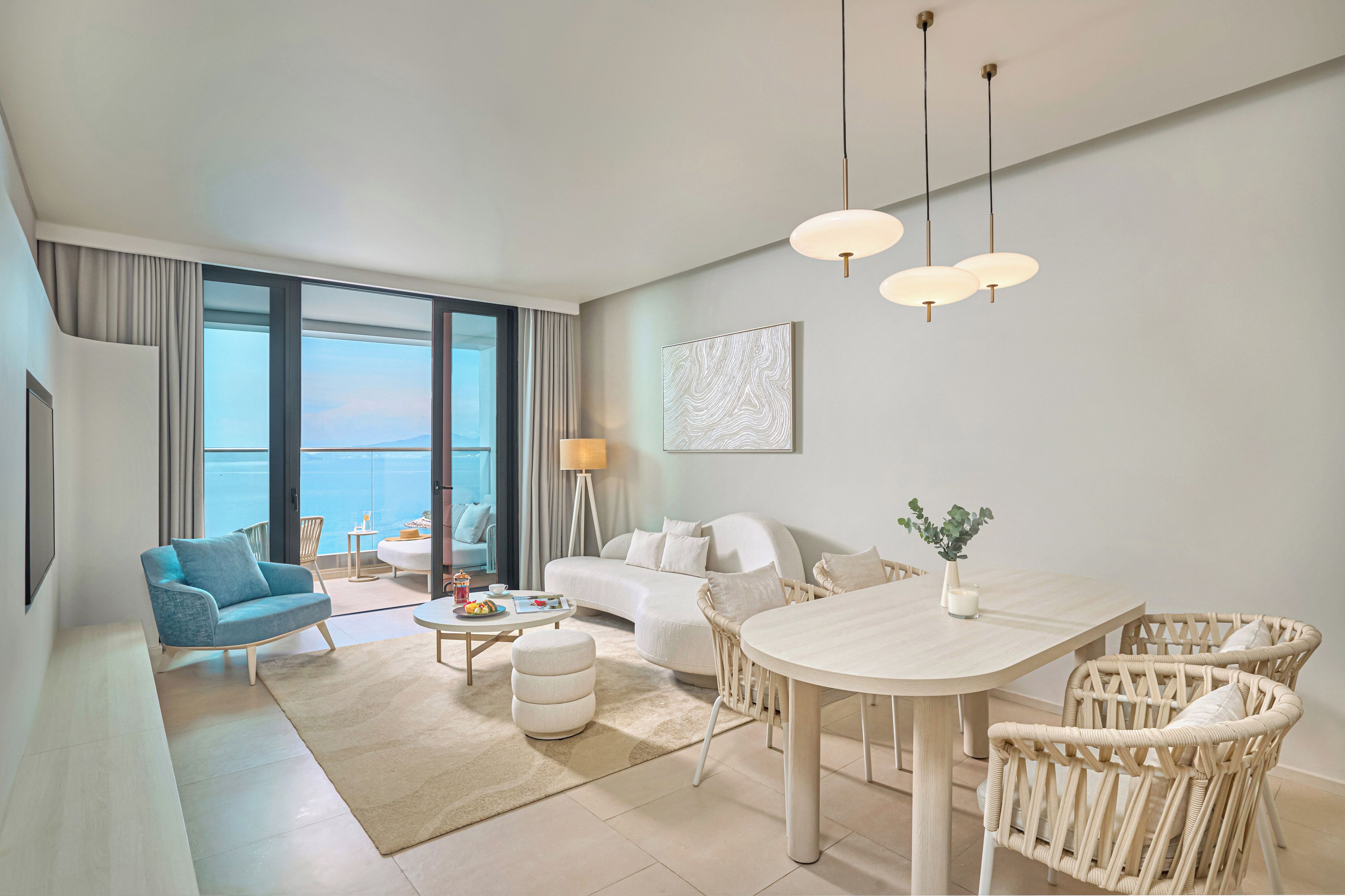 A modern hotel room with a balcony, a dining area, and a living space.