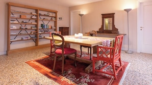 Un espace repas comprenant une table, des chaises, une bibliothèque, un miroir et un lampadaire.