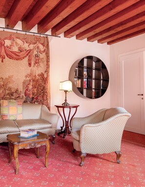 A room with a sofa, armchair, round table, and a bookshelf. - Foscolo Apartments (Venice)