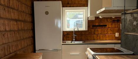 A compact kitchen with a refrigerator, sink, and wooden accents.