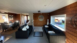Una sala de estar moderna con comedor, paredes de madera y un ventanal grande.