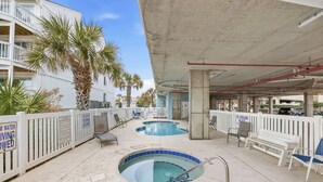 A rooftop pool area with two pools, lounge chairs, and palm trees. - Tropical Tide Large Group Beach Retreat Sleeps 24 (North Myrtle Beach)