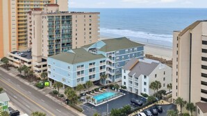 A multi-story hotel with a rooftop pool, located near a beach with ocean views. - Tropical Tide Large Group Beach Retreat Sleeps 24 (North Myrtle Beach)