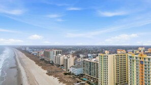 A coastal cityscape with high-rise buildings along the beach, featuring balconies and a clear view of the ocean. - Tropical Tide Large Group Beach Retreat Sleeps 24 (North Myrtle Beach)