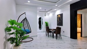 A modern interior with a hanging chair, a dining area, and a large mirror on the wall. - Dwellux Apartment (Abuja)