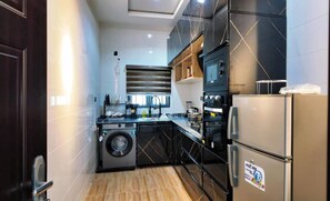 A modern kitchen with a washing machine, a refrigerator, and a microwave. - Dwellux Apartment (Abuja)