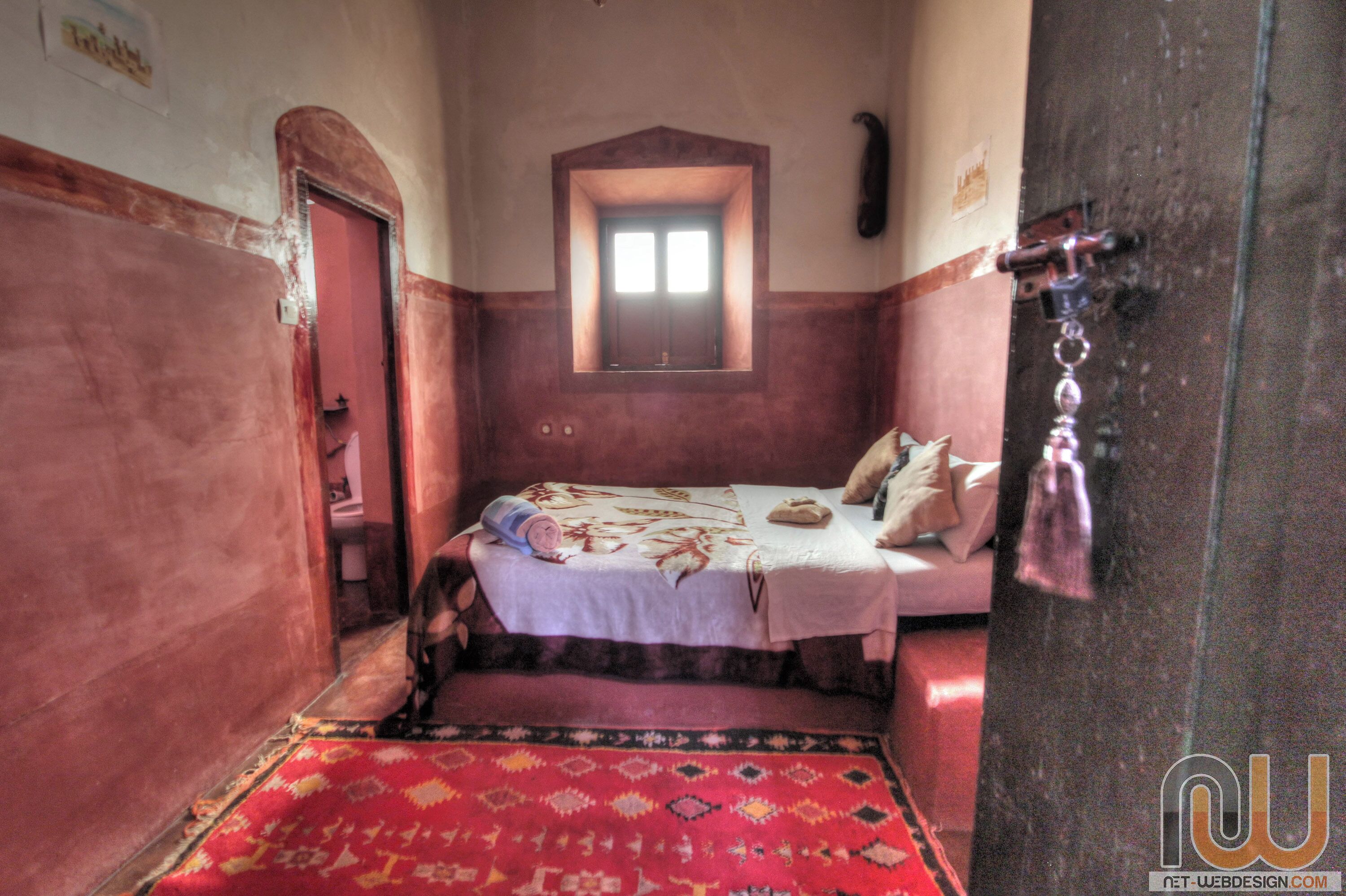 Una habitación pequeña y acogedora con cama, ventana y puerta.