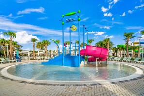 A water play area with slides and a pool, surrounded by palm trees and lounge chairs. - 16148 Palm Frond Avenue (Clermont)