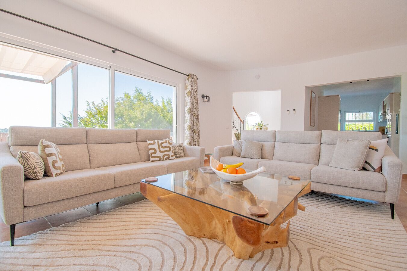 A modern living room with two sofas, a glass coffee table, and a large window.