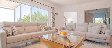A modern living room with two sofas, a glass coffee table, and a large window.