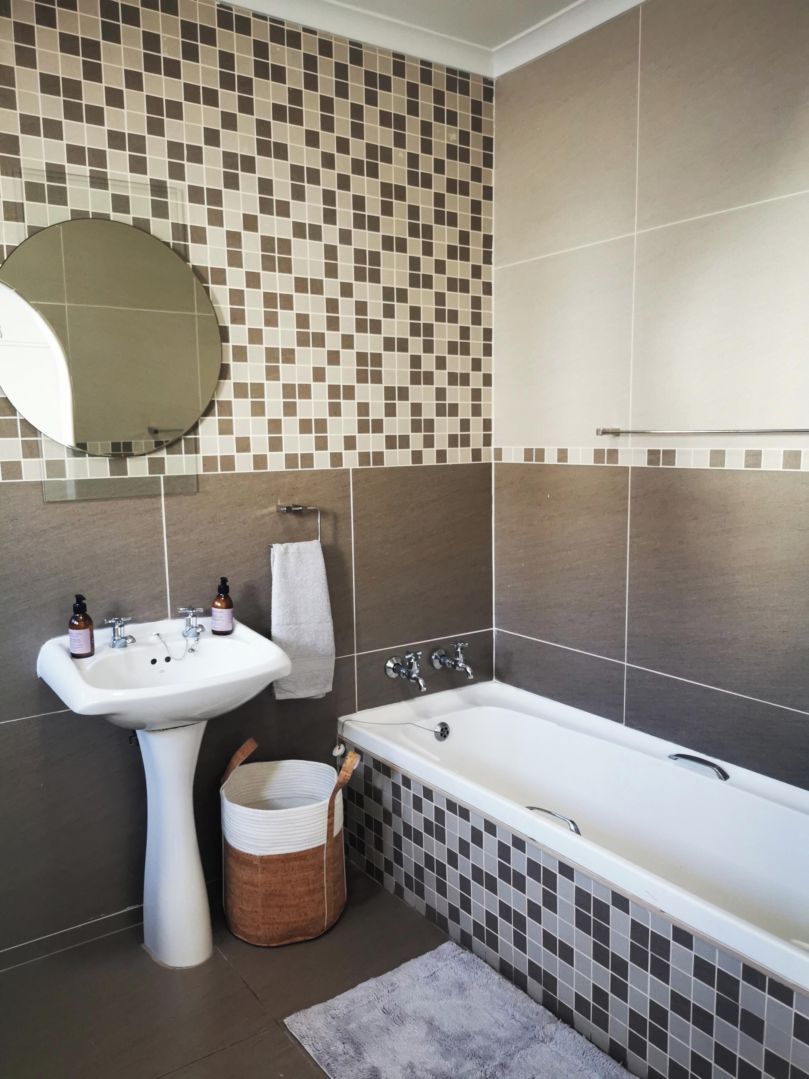 A bathroom with a sink, mirror, and bathtub.