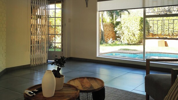 Un soggiorno moderno con una ventola a soffitto, ampie finestre che danno su una piscina e un muro in mattoni.