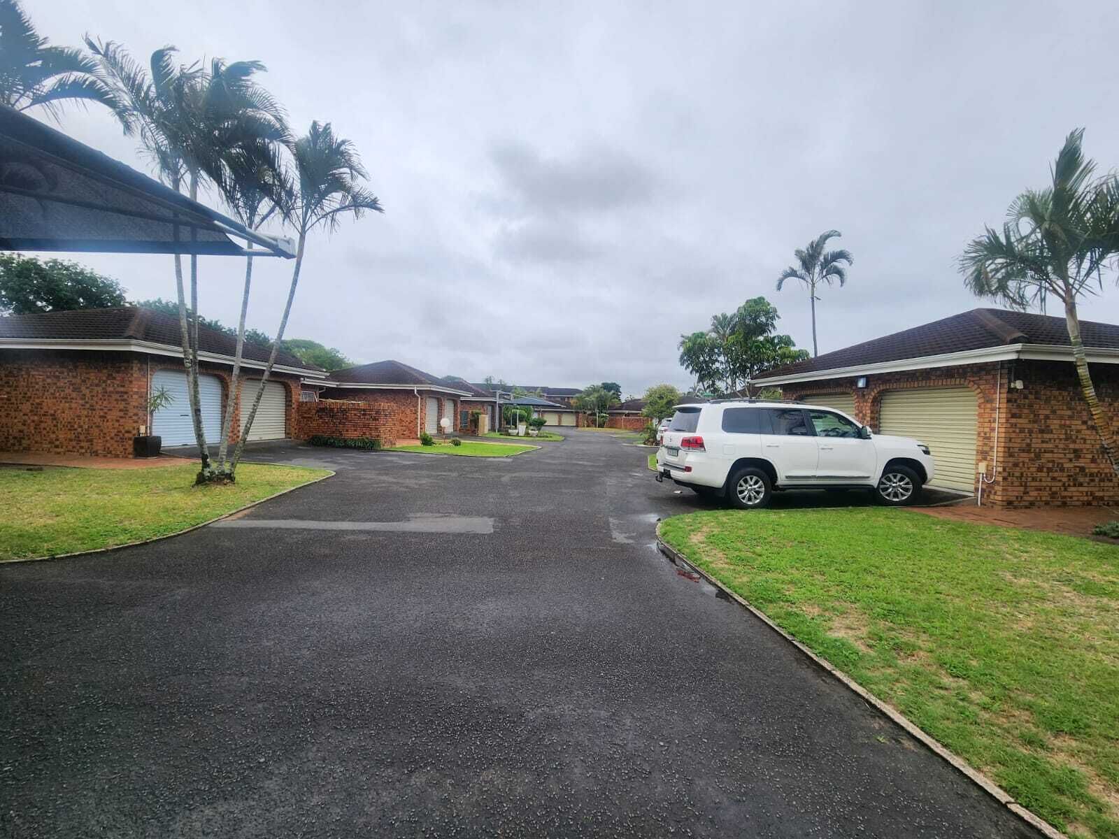 A residential street with houses, a parked white SUV, and palm trees.