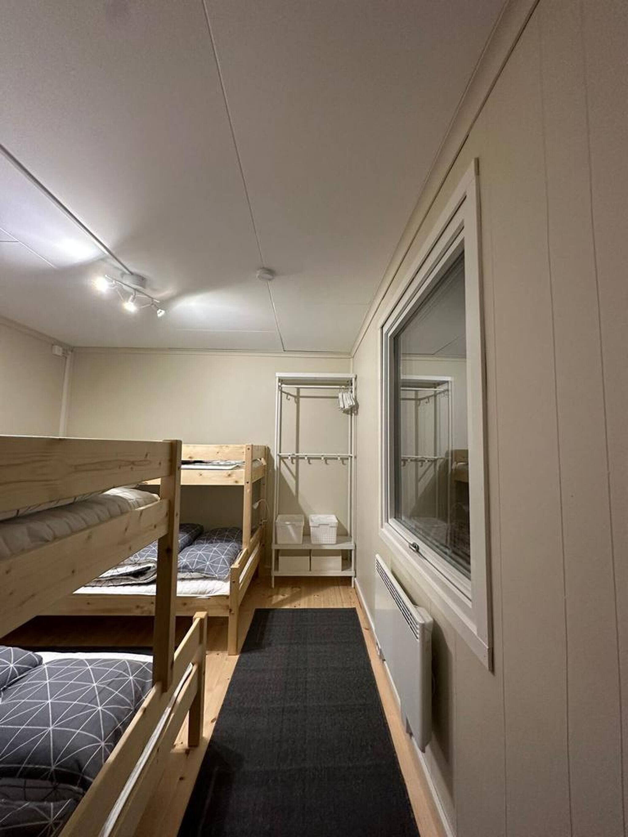 A compact room with bunk beds, a window, and a radiator.