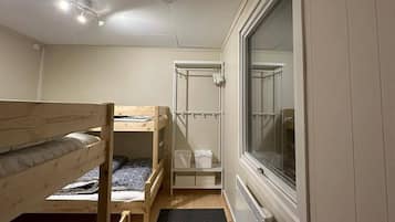 A compact room with bunk beds, a window, and a radiator.