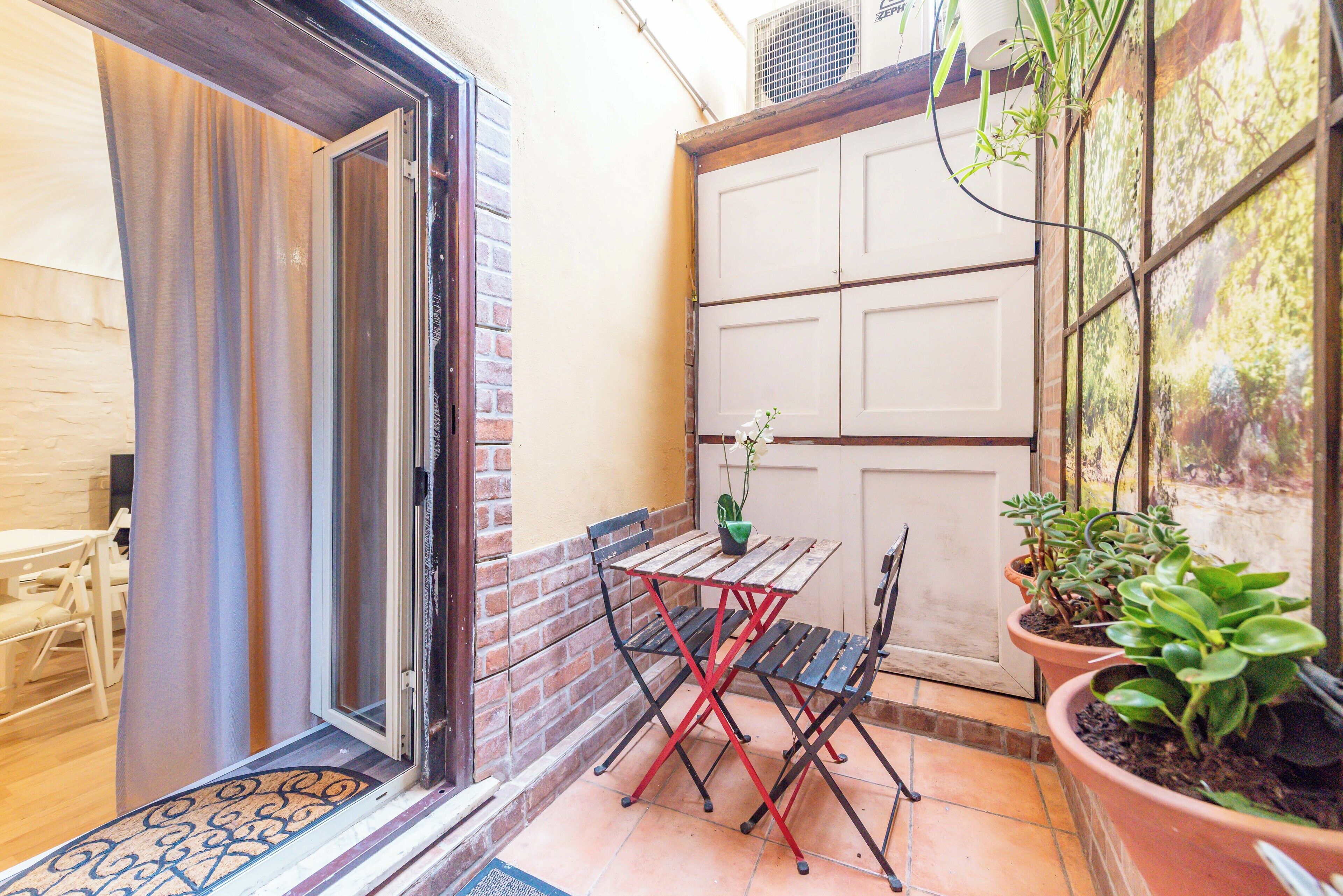 A patio area with a table and chairs, a sliding door, and potted plants.