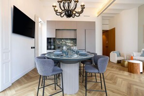 A modern dining area with a round table, grey chairs, and a central column. - Spectacular 3BD Apartment in Sevilla Antonia Diaz IV (Seville)