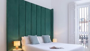 A modern bedroom with a large bed, two bedside lamps, and a green upholstered headboard. - Spectacular 3BD Apartment in Sevilla Antonia Diaz IV (Seville)