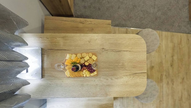 A wooden table with a cheese platter and two glasses of water. - Parkdean Crimdon Heated Sea View Caravan (Hartlepool)