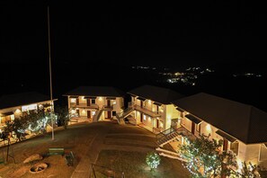 A multi-story hotel with a central courtyard, outdoor seating, and a well-lit entrance.