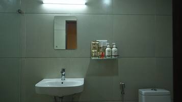 A bathroom with a white sink, a mirror, and a shelf with toiletries.